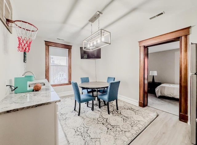 dining area with baseboards, light wood finished floors, and visible vents