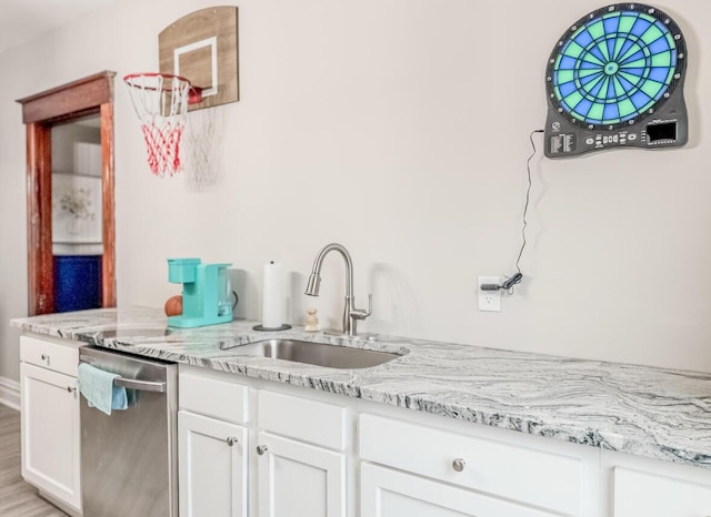 kitchen featuring a sink, stainless steel dishwasher, white cabinetry, and light stone countertops