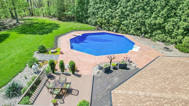 pool featuring a lawn, a deck, and a diving board
