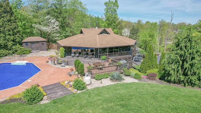 back of house featuring an outbuilding, an outdoor pool, a storage structure, a yard, and a patio