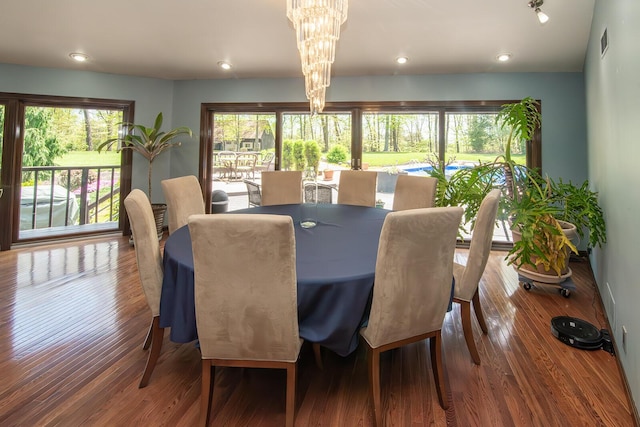 dining space with visible vents, wood finished floors, a notable chandelier, and a wealth of natural light