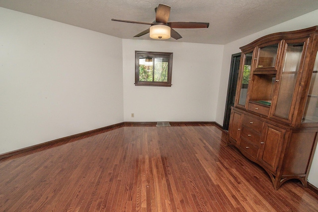 spare room featuring ceiling fan, a textured ceiling, visible vents, dark wood finished floors, and baseboards