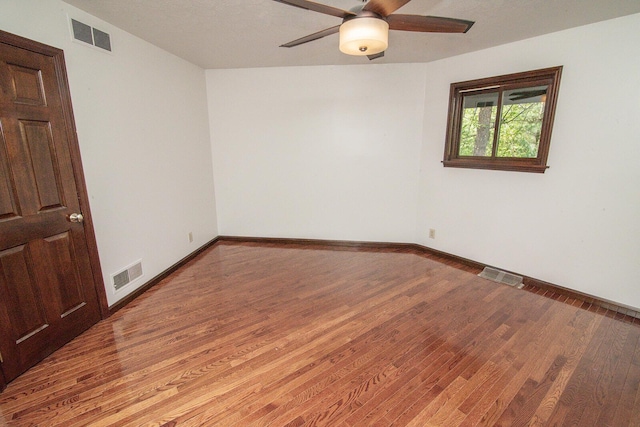 empty room with visible vents, ceiling fan, and wood finished floors