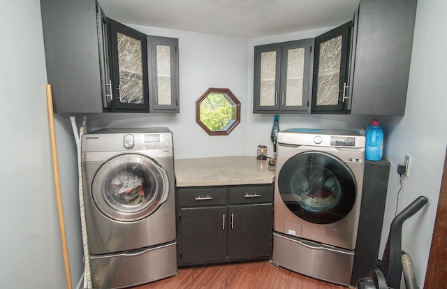 laundry area featuring independent washer and dryer, cabinet space, and wood finished floors