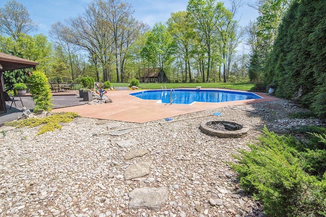pool featuring a wooden deck, an outdoor fire pit, and a patio