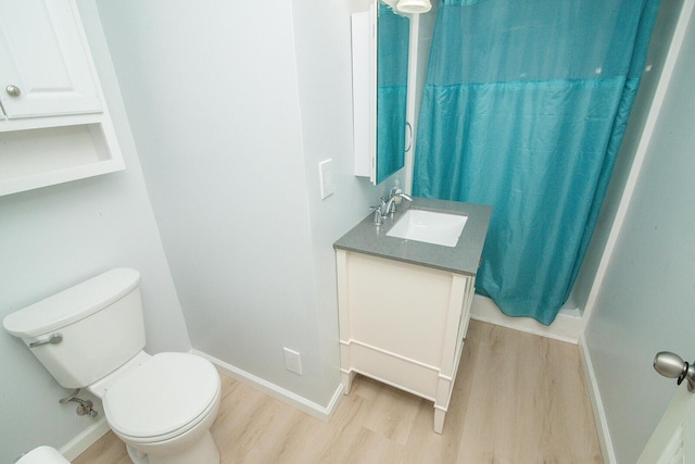 full bath with toilet, baseboards, wood finished floors, and vanity