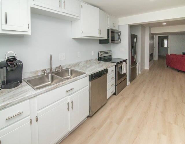kitchen with light countertops, stainless steel appliances, a sink, and light wood finished floors