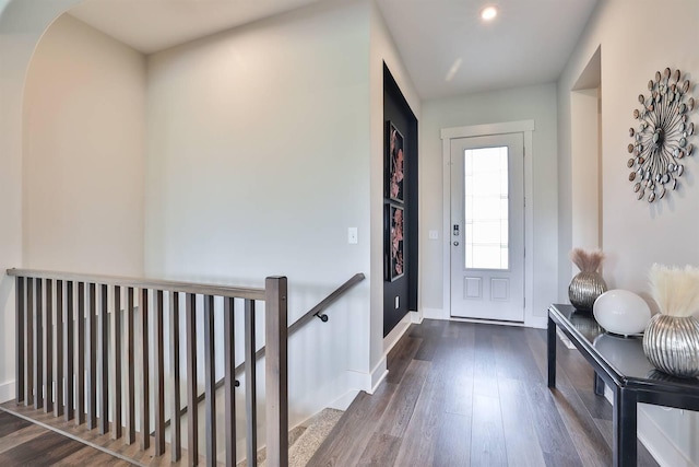 foyer featuring dark wood-style flooring, baseboards, recessed lighting, and arched walkways