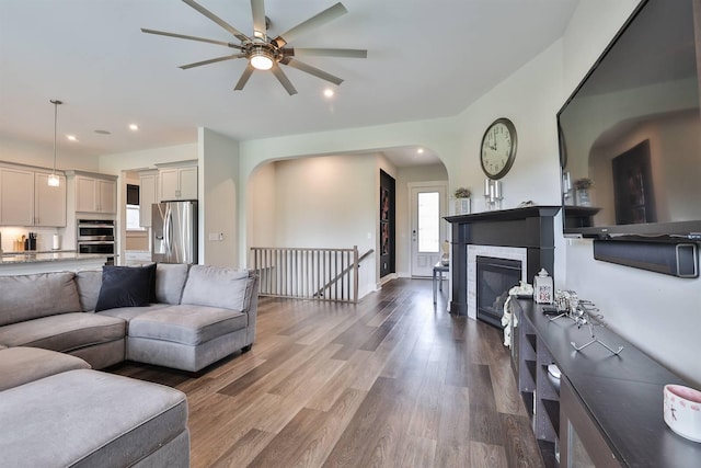 living room featuring arched walkways, a ceiling fan, recessed lighting, and wood finished floors