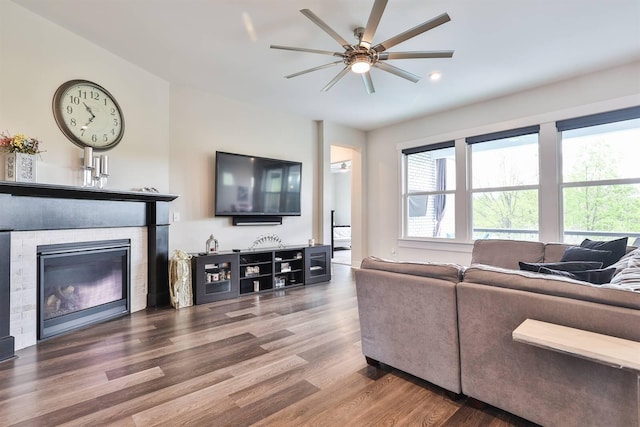 living room with a glass covered fireplace, ceiling fan, recessed lighting, and wood finished floors