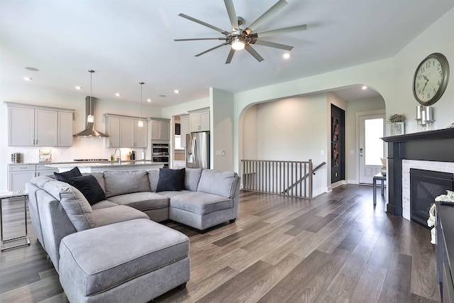 living room with arched walkways, a ceiling fan, recessed lighting, and dark wood-style floors
