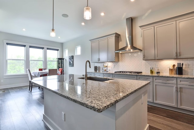 kitchen with stainless steel gas cooktop, gray cabinets, wall chimney exhaust hood, tasteful backsplash, and a sink
