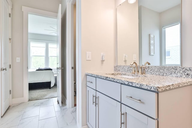 ensuite bathroom featuring baseboards, vanity, ensuite bath, and marble finish floor