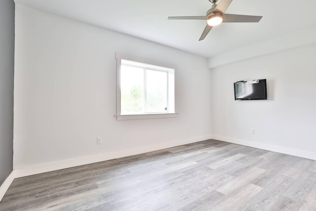 spare room with baseboards, ceiling fan, and wood finished floors