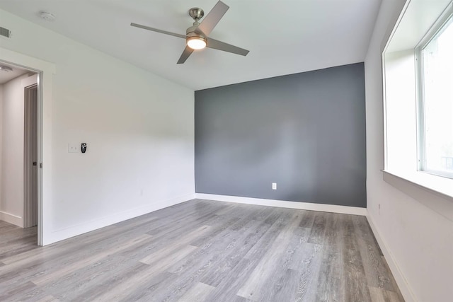 spare room featuring baseboards, a ceiling fan, wood finished floors, and visible vents