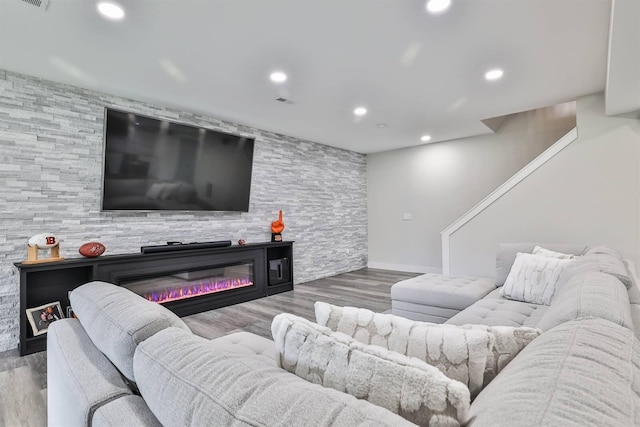 living room featuring visible vents, wood finished floors, baseboards, a glass covered fireplace, and recessed lighting