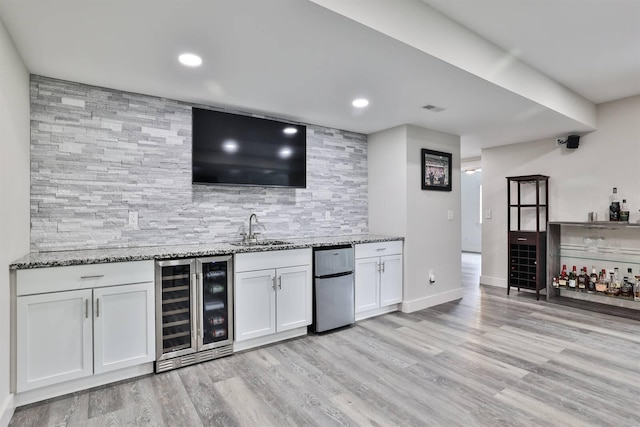 bar with fridge, a sink, beverage cooler, wet bar, and backsplash