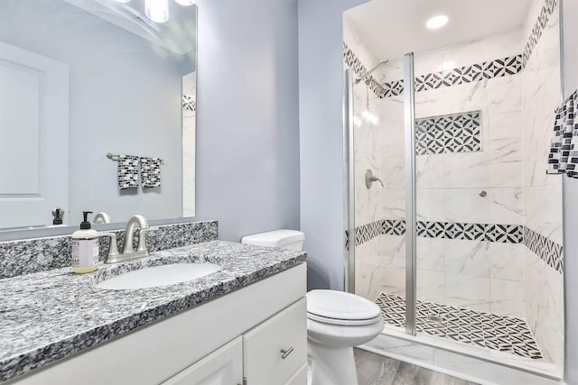 full bath featuring vanity, a shower stall, toilet, and wood finished floors