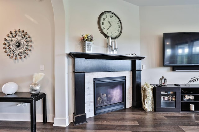 living area featuring arched walkways, a dry bar, wood finished floors, and a fireplace