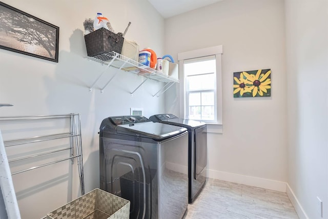 washroom with separate washer and dryer, laundry area, baseboards, and wood finished floors