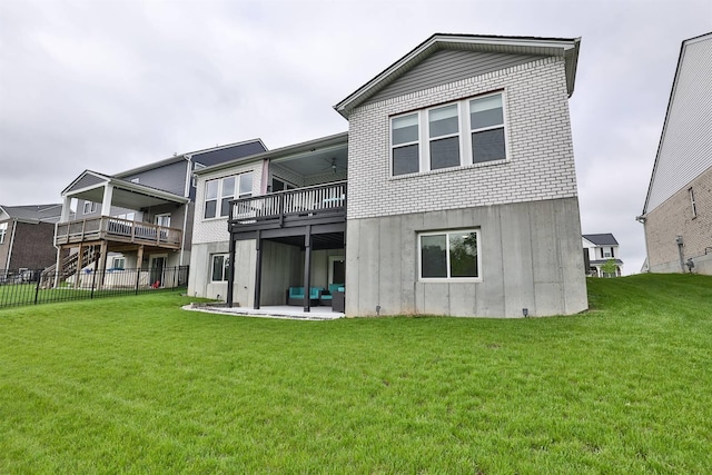 back of property featuring fence, ceiling fan, a patio area, a balcony, and a yard