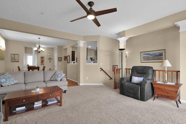 living area featuring carpet floors, baseboards, ceiling fan with notable chandelier, and decorative columns
