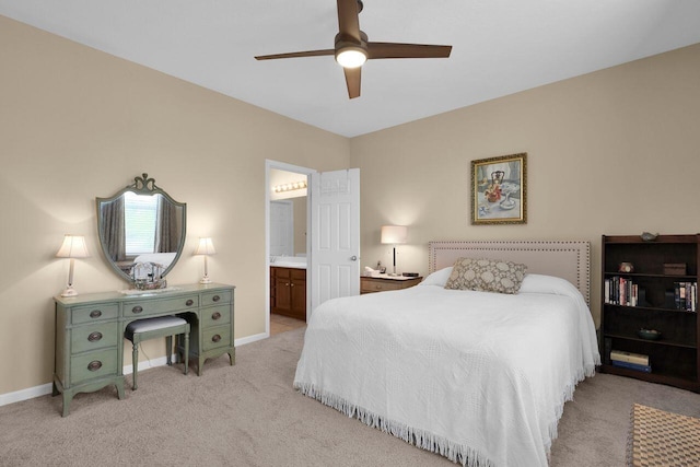 bedroom with baseboards, light colored carpet, ceiling fan, and ensuite bath