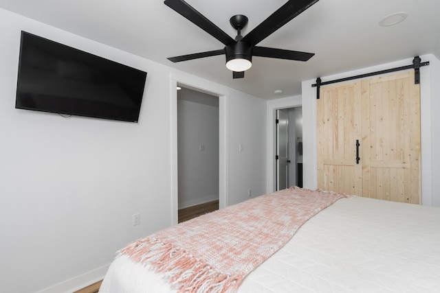 bedroom with a barn door, baseboards, and ceiling fan