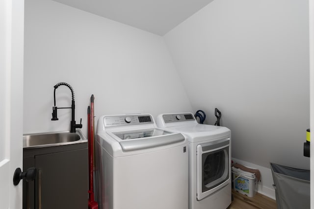laundry area featuring washing machine and clothes dryer, cabinet space, and wood finished floors