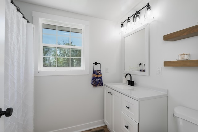 bathroom with toilet, vanity, and baseboards