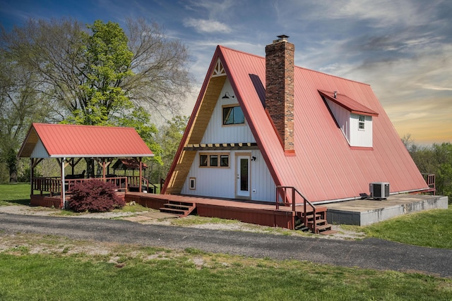view of front of property with a chimney, metal roof, a deck, central air condition unit, and a front yard