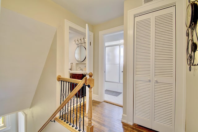 corridor featuring baseboards, an upstairs landing, and dark wood-type flooring