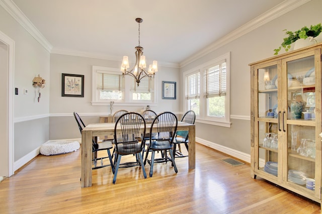 dining room with an inviting chandelier, ornamental molding, light wood-type flooring, and visible vents
