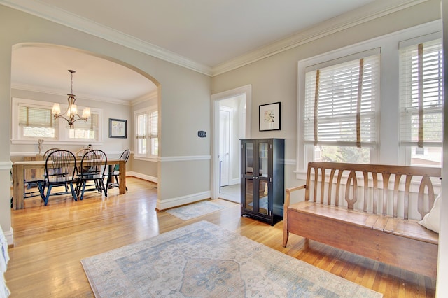 foyer entrance with arched walkways, wood finished floors, baseboards, a chandelier, and ornamental molding