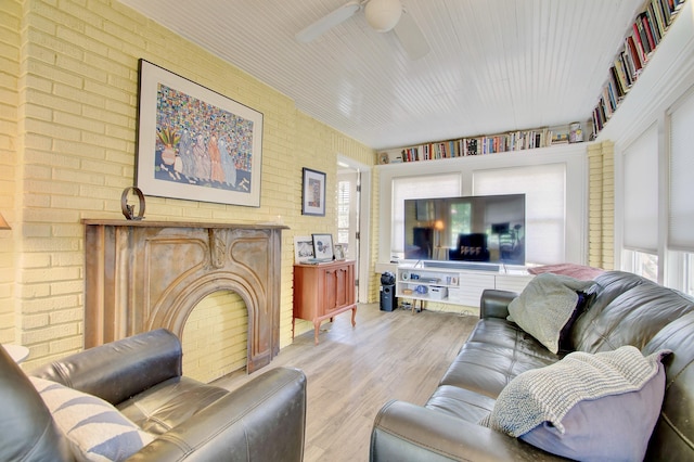 living room with a ceiling fan, brick wall, and wood finished floors