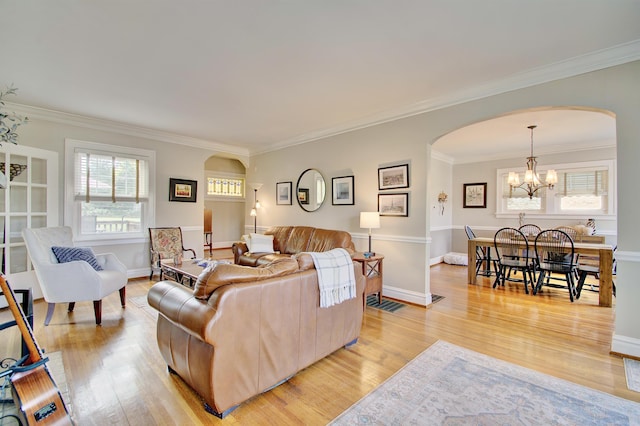 living room featuring an inviting chandelier, arched walkways, crown molding, and light wood-type flooring