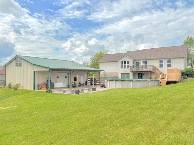 back of property with a lawn, a covered pool, a patio area, and metal roof