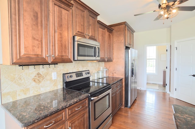 kitchen featuring ceiling fan, appliances with stainless steel finishes, baseboards, decorative backsplash, and light wood-type flooring