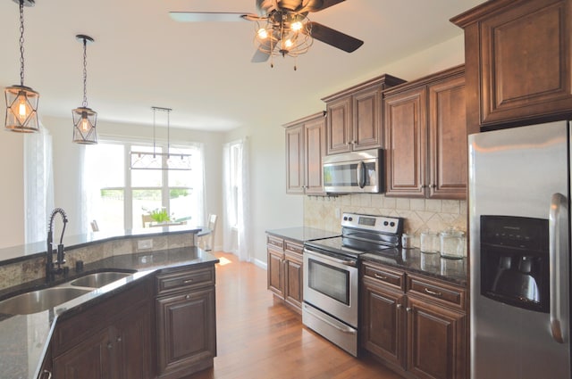 kitchen featuring decorative backsplash, wood finished floors, ceiling fan, a sink, and appliances with stainless steel finishes