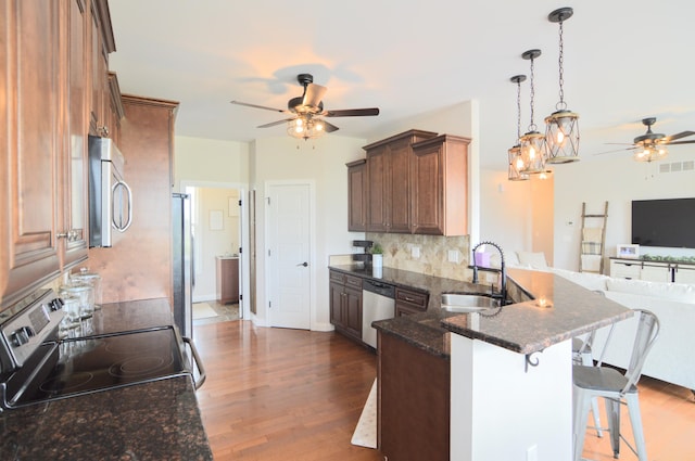 kitchen with a ceiling fan, a sink, a peninsula, open floor plan, and stainless steel appliances