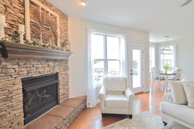 living area featuring recessed lighting, baseboards, a stone fireplace, and wood finished floors