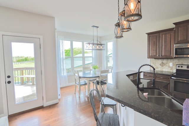 kitchen featuring dark brown cabinets, light wood-type flooring, a chandelier, a sink, and stainless steel appliances