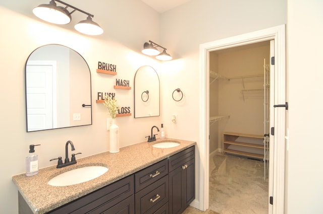bathroom with a sink, a walk in closet, and double vanity
