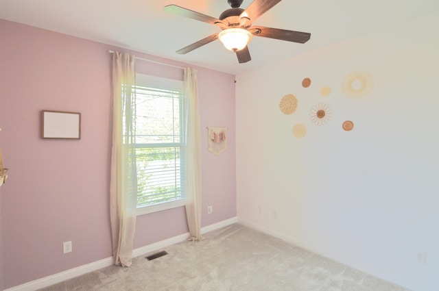 empty room featuring baseboards, plenty of natural light, light colored carpet, and visible vents