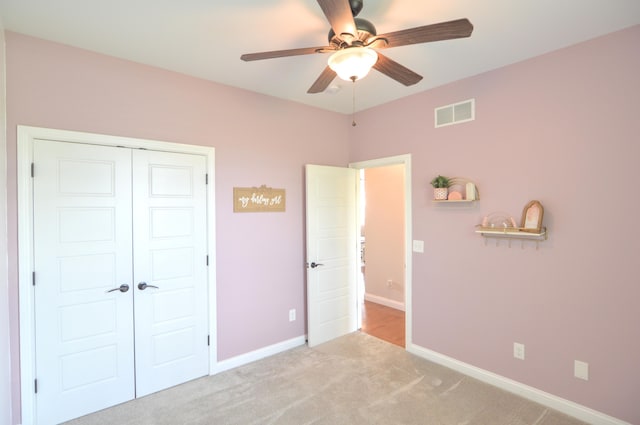 unfurnished bedroom with ceiling fan, visible vents, light colored carpet, baseboards, and a closet