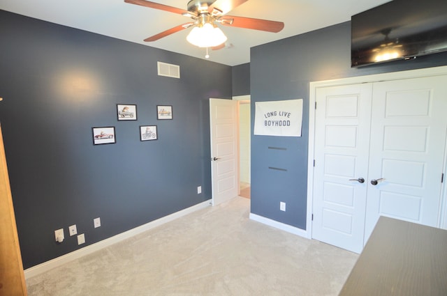 unfurnished bedroom featuring visible vents, a closet, baseboards, light colored carpet, and a ceiling fan