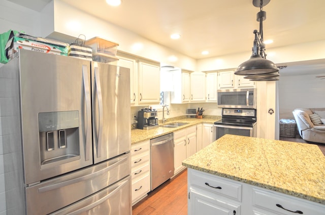 1376 Symbo Ln, Walton, KY 41094 - kitchen featuring pendant lighting, light stone countertops, light wood-style floors, a sink, and appliances with stainless steel finishes