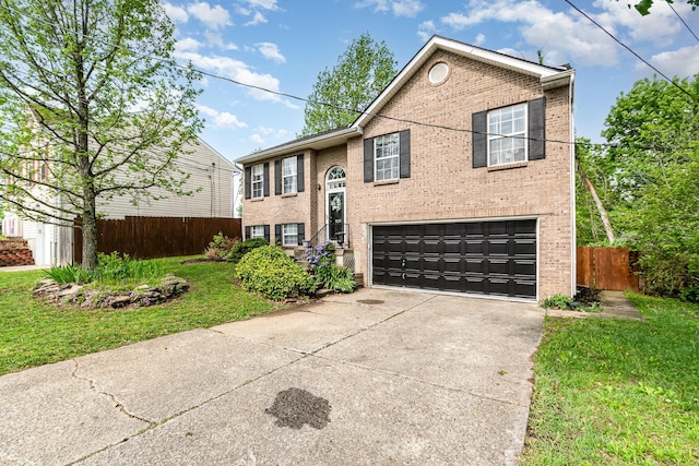 split foyer home featuring a garage, fence, concrete driveway, and brick siding