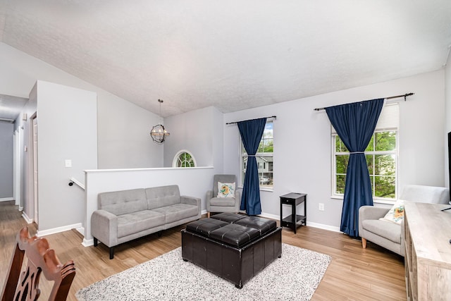 living room with baseboards, a notable chandelier, light wood-style flooring, and lofted ceiling
