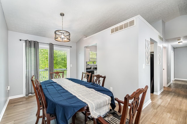 dining area featuring light wood-style floors, baseboards, a textured ceiling, and visible vents